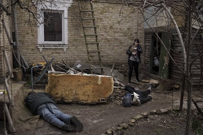 Ira Gavriluk sostiene a su gato mientras camina junto a los cuerpos de su esposo, hermano y otro hombre, que fueron asesinados frente a su casa en Bucha, en las afueras de Kiev.