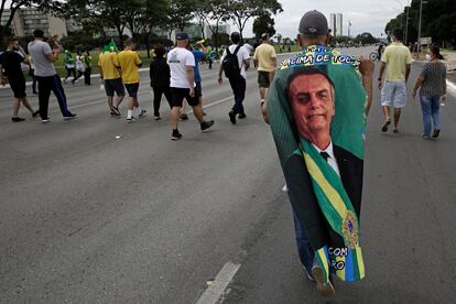 Manifestante carrega bandeira com imagem do presidente Jair Bolsonaro durante caravana em seu apoio em Brasília, no Primeiro de Maio.