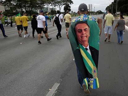 Manifestante carrega bandeira com imagem do presidente Jair Bolsonaro durante caravana em seu apoio em Brasília, no Primeiro de Maio.