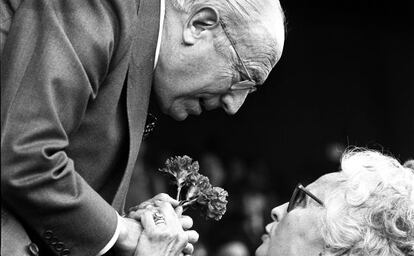 Enrique Tierno Galv&aacute;n, recibe un ramo de claveles de manos de una mujer, durante un acto en 1981
    