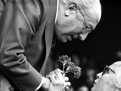 Enrique Tierno Galv&aacute;n, recibe un ramo de claveles de manos de una mujer, durante un acto en 1981
    