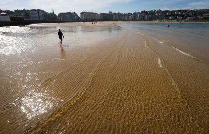 Un hombre pasea por la orilla de la playa de La Concha de San Sebastián, donde las temperaturas máximas iniciarán un notable ascenso durante la jornada de hoy.
