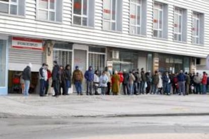 Varias personas forman una larga cola ante una oficina del INEM. EFE/Archivo