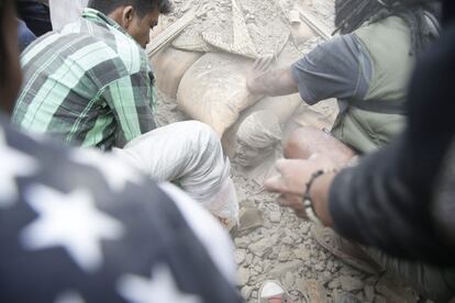 Un hombre enterrado entre las ruinas de un edificio en Katmandú.