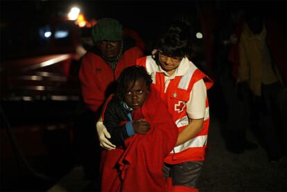 Un miebro de la Cruz Roja sostiene a uno de los menores llegados en patera al puerto de Motril (Granada).