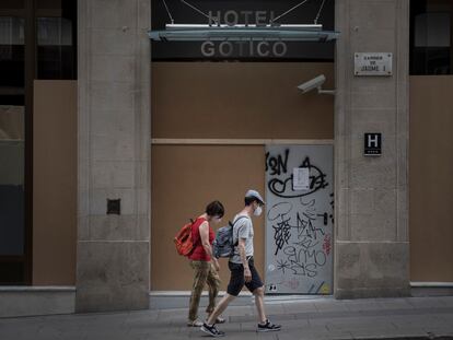Unos turistas delante de un hotel cerrado en el barrio Gótico de Barcelona.