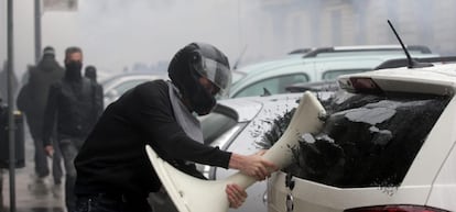 Un manifestante destroza la ventana de un vehículo durante una protesta con motivo de la inauguración oficial de la Exposición Universal de Milán 2015.