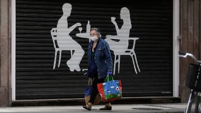 Una mujer pasa con la compra frente a un bar cerrado en San Sebastián.