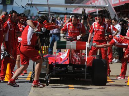 Fernando Alonso rodeado de mecánicos de Ferrari en los entrenamientos de ayer.