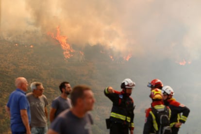 Bomberos y vecinos observan las llamas del incendio de La Baña (León), este domingo.