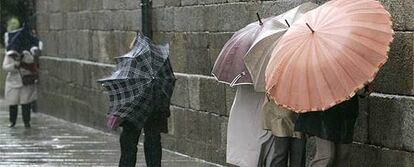 Varias personas se protegen del viento contra la pared en Santiago de Compostela.