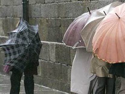 Varias personas se protegen del viento contra la pared en Santiago de Compostela.