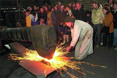 El ferrón moldea un trozo de hierro a gran temperatura con ayuda de un enorme mazo en el interior de la ferrería de Mirandaola.