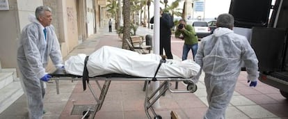 Empleados de la funeraria trasladan el cadáver.