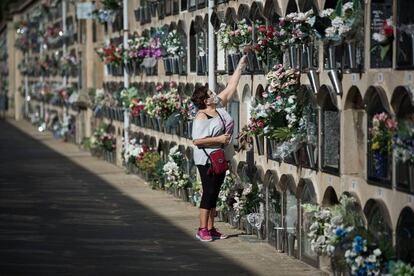 Una dona dipositant flors en un nínxol del cementiri del Poblenou.