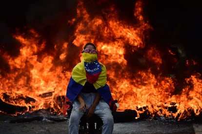 Una activista de la oposición venezolana permance sentada junto a una barricada en llamas en Caracas, el 24 de abril de 2017.