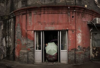 Un niño chino se asoma a la puerta de su casa en Pekín, China.