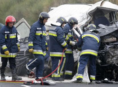 Los bomberos, junto a la furgoneta en la que viajaban los seis muertos en el accidente de Palencia.