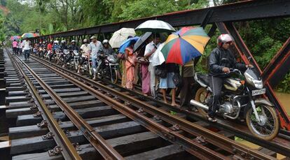 Las lluvias monzónicas han causado estragos en Sri Lanka. En la imagen, afectados por las inundaciones cruzan un puente por las vías del tren en Puwakpitiya.