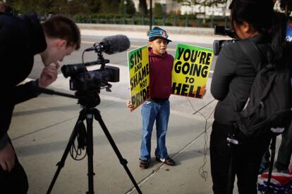 Daniel Phelps, de nueve años y uno de los muchísimos nietos de Fred Phelps, sujeta pancartas con mensajes como: "Vergüenza y pecado, no orgullo" y "vas a ir al infierno".