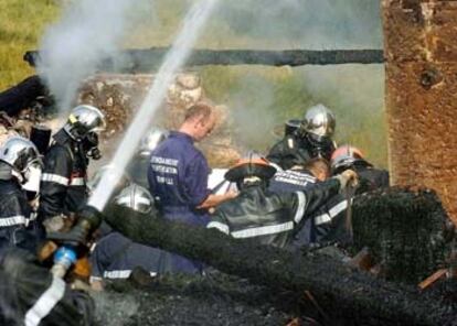 Bomberos franceses tratan de apagar el fuego que incendió ayer una colonia de equitación en la que murieron nueve personas.