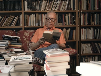 El escritor Juan José Millás leyendo entre las montañas de libros que configuran su biblioteca, antes de la entrevista.