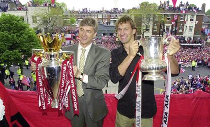 El entrenador del Arsenal, Arsene Wenger, y el capitán, Tony Adams, muestran los trofeos de la Premiere League y de la FA Cup conseguidos en la temporada 2001-2002 desde un balcón frente a su afición, el 12 de mayo de 2002.