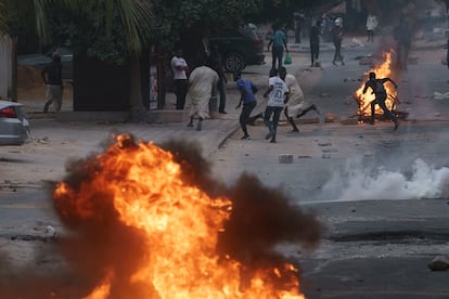 Manifestantes corren en una calle de Dakar mientras la policía les lanza gases lacrimógenos, este jueves 1 de junio.