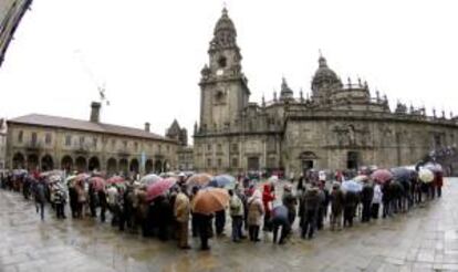 Centenares de turistas soportan una fuerte lluvia para acceder a la catedral de Santiago de Compostela por la Puerta Santa. EFE/Archivo