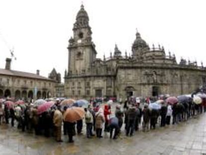 Centenares de turistas soportan una fuerte lluvia para acceder a la catedral de Santiago de Compostela por la Puerta Santa. EFE/Archivo