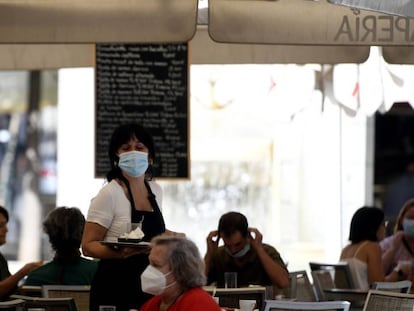Una camarera con mascarilla atiende a los clientes en una terraza de un bar en Madrid.