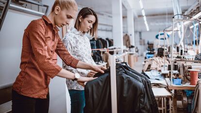 Diseñadoras de moda realizando un control de calidad en una fábrica textil.