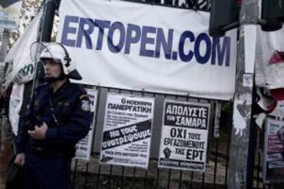 Un policía antidisturbios permanece junto a pancartas de protesta a la entrada de la sede de la televisión pública ERT en Atenas. EFE/Archivo