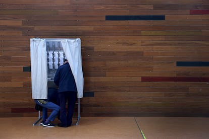 Dos personas en el interior de una cabina eligen su voto este domingo en el colegio electoral de Otxandio, en Bizkaia.
