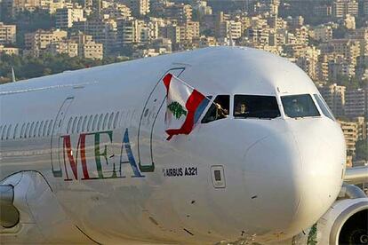 Un tripulante de un avión de la compañía Middle East Airlines ondea una bandera libanesa tras aterrizar en el aeropuerto de Beirut.