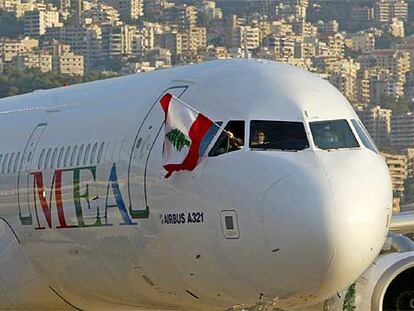 Un tripulante de un avión de la compañía Middle East Airlines ondea una bandera libanesa tras aterrizar en el aeropuerto de Beirut.
