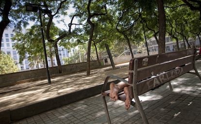 Un hombre reposa en un banco de la plaza de Josep Maria Folch i Torres. 