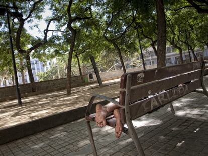Un hombre reposa en un banco de la plaza de Josep Maria Folch i Torres. 