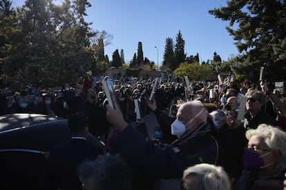 Los congregados llevan libros de Almudena Grandes en la mano, que muestran mientras pasa el féretro de la escritora, a su llegada al cementerio de la Almudena.