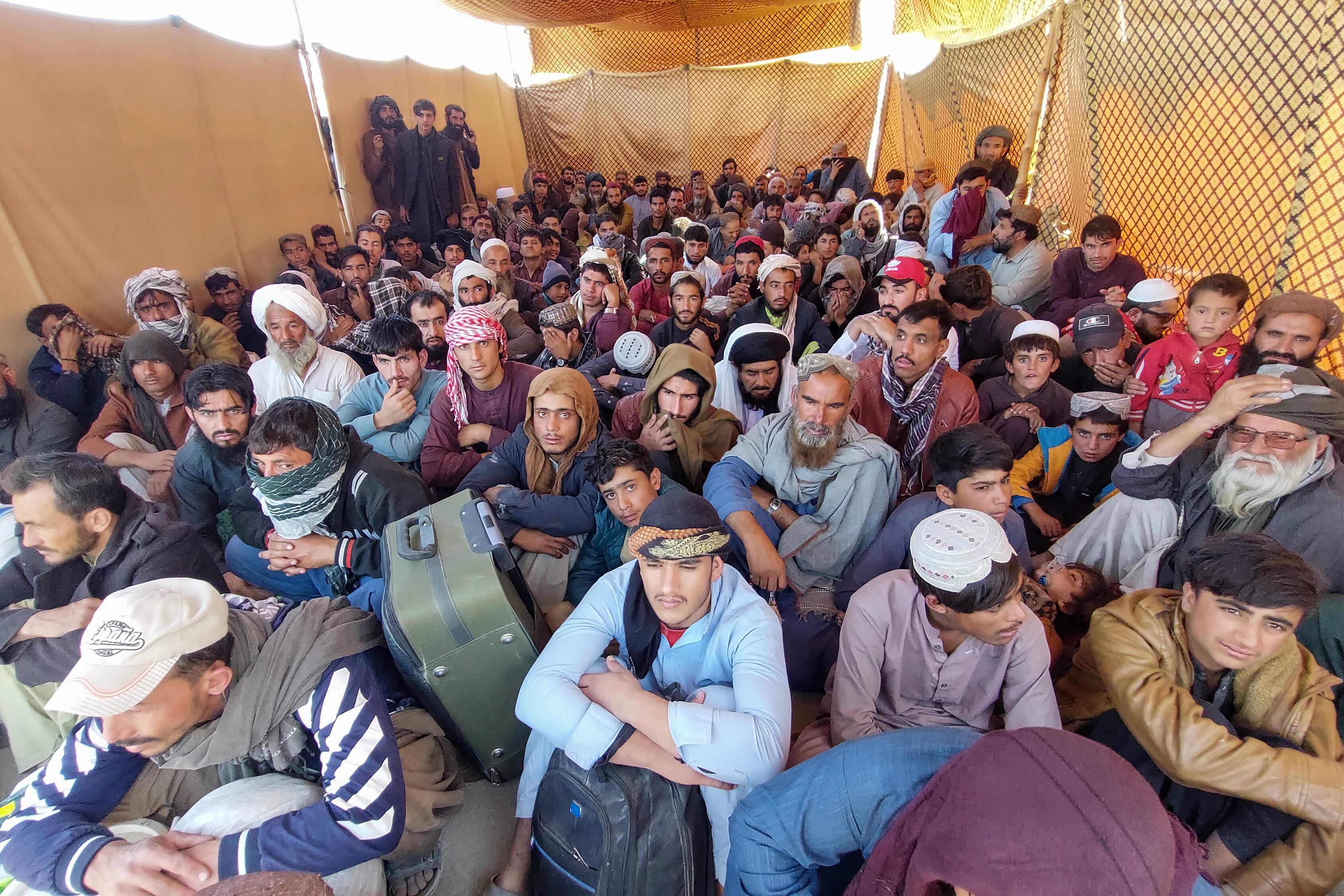 Decenas de migrantes afganos esperan para cruzar hacia su país de origen, este lunes en Chaman (Pakistán). 