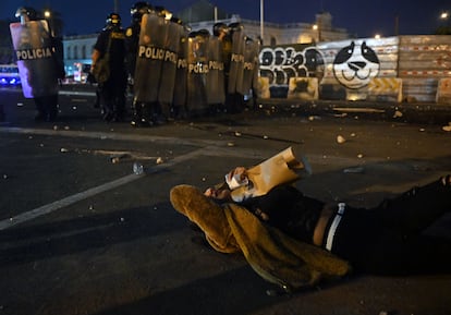 Una manifestante afectada por el lanzamiento de gases lacrimógenos yace en el asfalto, durante una protesta, este lunes.
