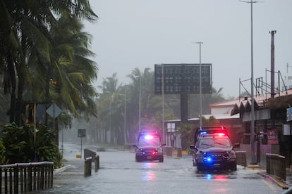 Patrullas de la policía local recorren las calles de Cancún para alertar a las personas ante la llegada del huracán. 