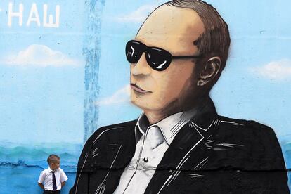 Un niño se apoya en una pared decorada con un graffiti del presidente ruso, Vladimir Putin, en la península de Crimea, territorio anexionado por Rusia.