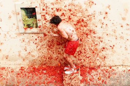 Un joven se cubre mientras vuelan tomates durante la Tomatina.