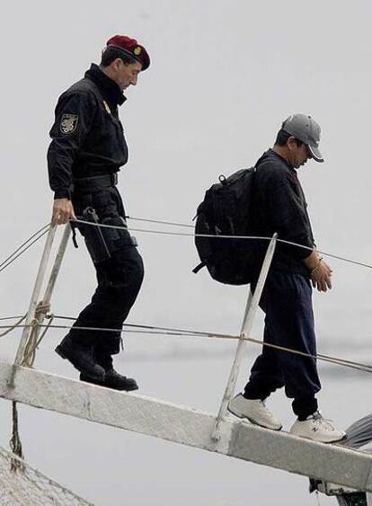 Un policía acompaña a un detenido que desembarca del <i>Oceanía</i> en Vigo.