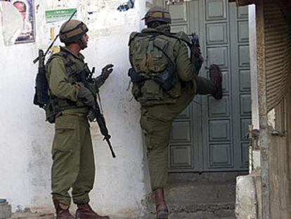 Dos soldados israelíes intentando abrir una puerta a patadas.