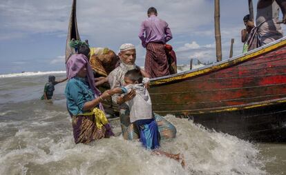 Un anciano musulmán Rohingya ayuda a un niño a bajar de un barco tras llegar de Myanmar a Bangladesh, en Shah Porir Dwip (Bangladesh).