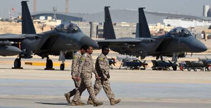 Tres oficiales saud&iacute;es caminan junto a unos cazas de reacci&oacute;n F-15, en enero en la base a&eacute;rea de Riad.