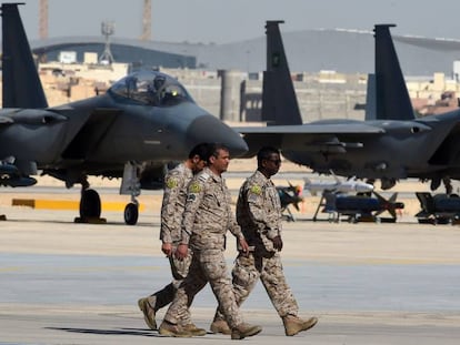 Tres oficiales saud&iacute;es caminan junto a unos cazas de reacci&oacute;n F-15, en enero en la base a&eacute;rea de Riad.