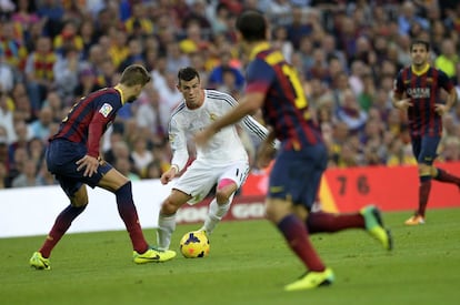 Gareth Bale intenta irse con el balón frente a Piqué y Mascherano.